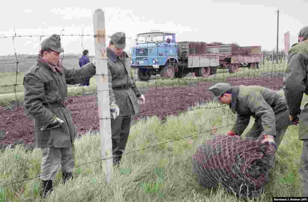 Вугорскія памежнікі зьбіраюць «жалезную заслону» падчас яе дэмантажу на аўстрыйскай мяжы ў траўні 1989 году. 
