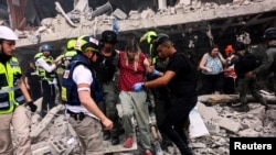 Spasioci evakuišu stanovnike iz zgrade koja je pogođena iranskom raketom.