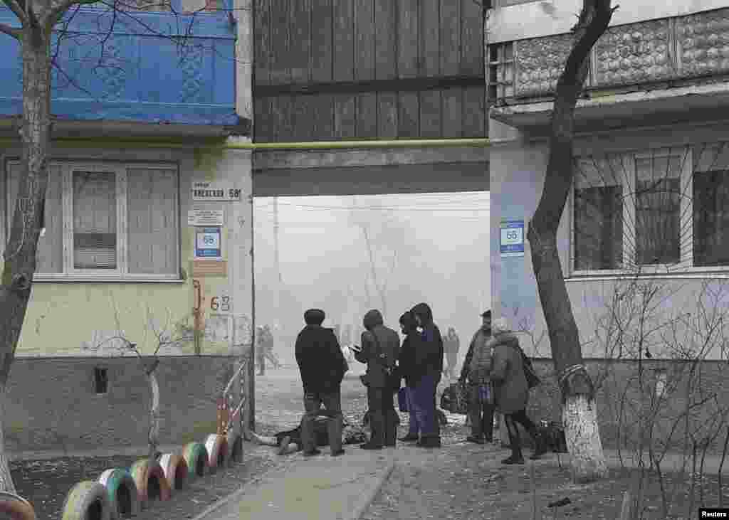 Люди стоять біля загиблого внаслідок обстрілу бойовиками житлового сектора в Маріуполі. Житловий район Маріуполя після обстрілу бойовиками. Десятки загиблих. Близько сотні поранені​. Маріуполь, 24 січня 2014 року