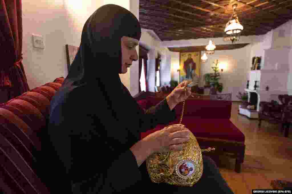 Черниця вшиває в митру дорогоцінні камені і маленькі ікони 