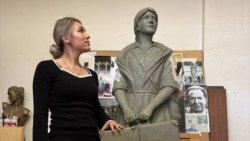 Dorina Roșca pozând alături de monumentul femeii migrante. 