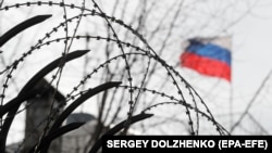 Російський прапор за колючим дротом на паркані посольства Росії в Києві